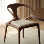 Walnutry Copenhagen solid walnut armchair with black leather seat and sculptural backrest.