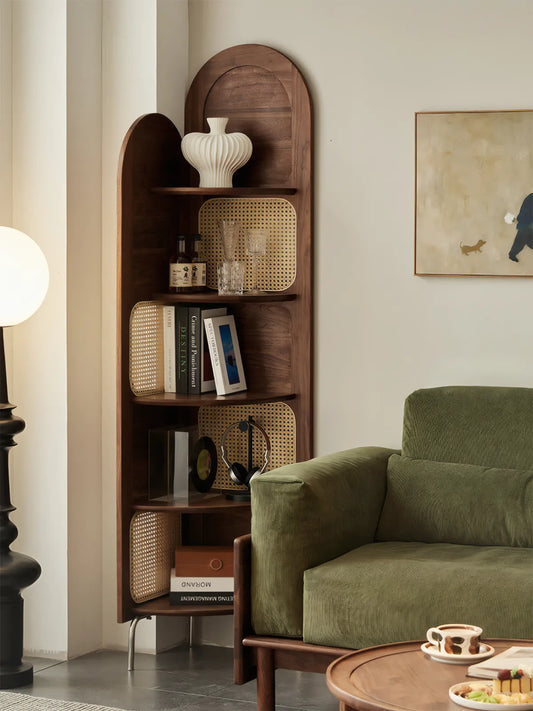 Dark walnut solid wood corner bookcase styled next to a green corduroy sofa, showcasing rich wood tones against soft textures.