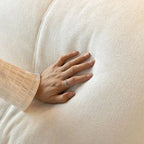 Hand pressing a soft, textured white down-filled cushion fabric, showing plush comfort detail