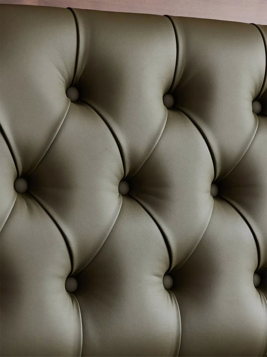 Close-up detail of deep diamond tufting on emerald green top-grain leather headboard.