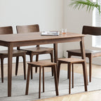 Modern wooden dining table with matching chairs and two stacking stools on a rug in a bright room
