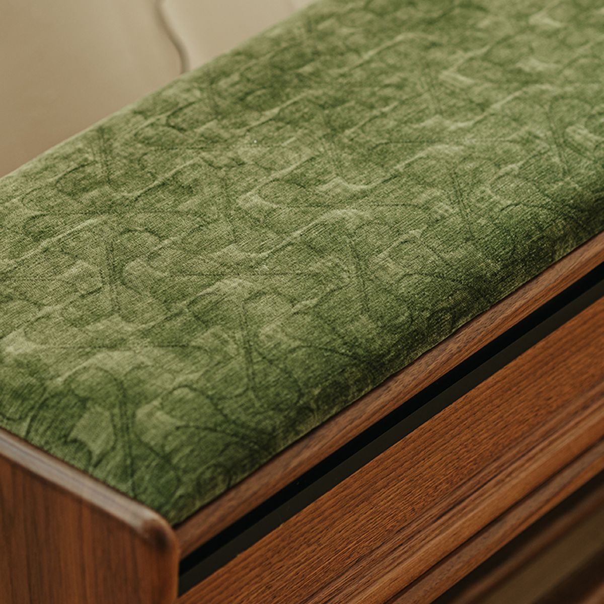Close-up of a green fabric cushion with subtle clover pattern on North American black walnut furniture