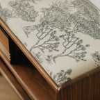 Close-up of cushioned wooden bench seat with black and white French toile fabric featuring tree pattern