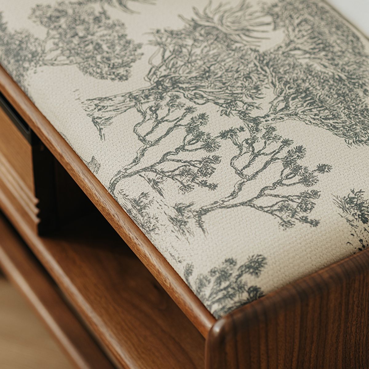 Close-up of French toile fabric cushion with intricate black tree pattern on solid walnut wood furniture