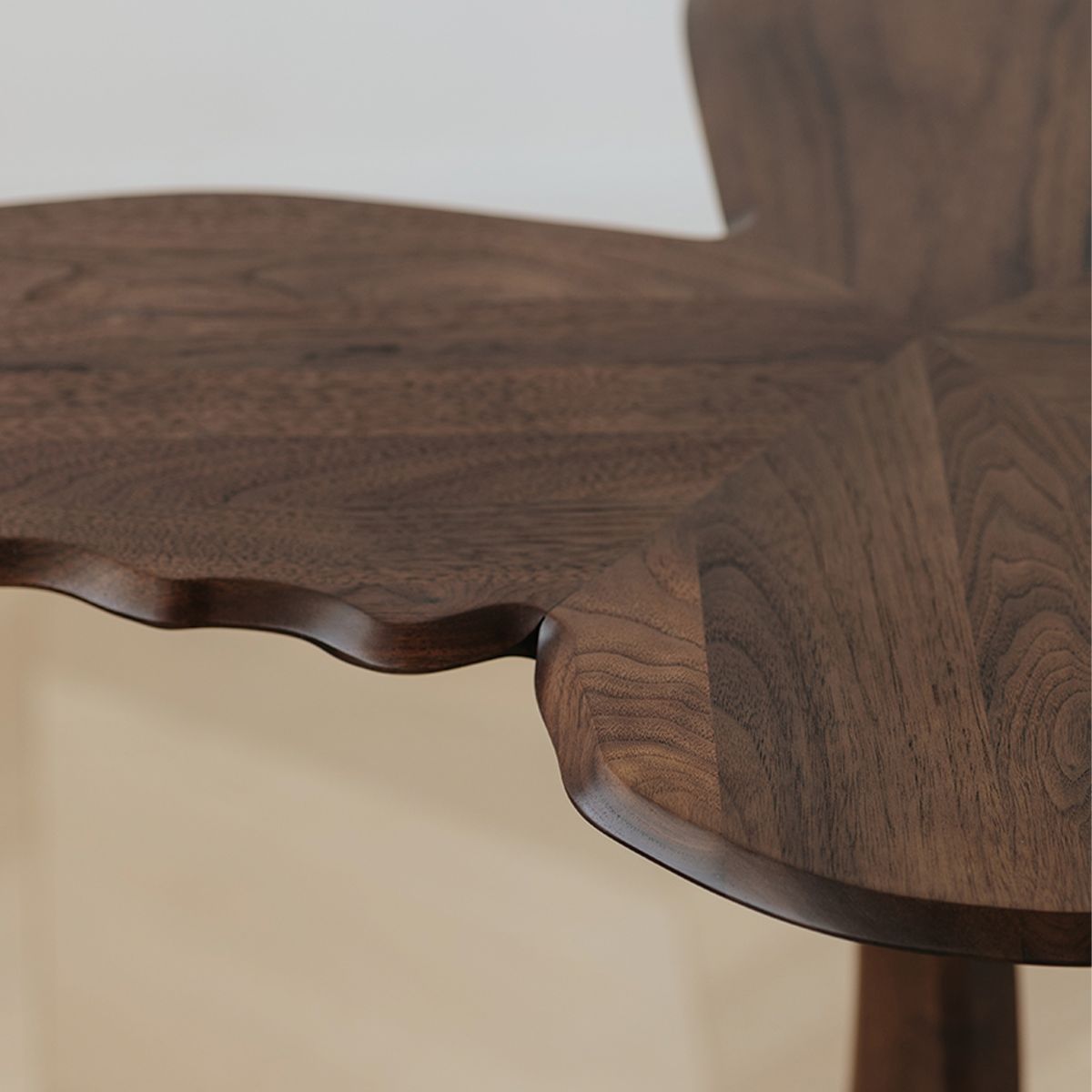 Close-up of hand-carved edge on walnut wood table with intricate grain pattern
