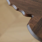 Close-up detail of the hand-carved edges on the solid walnut butterfly end table.