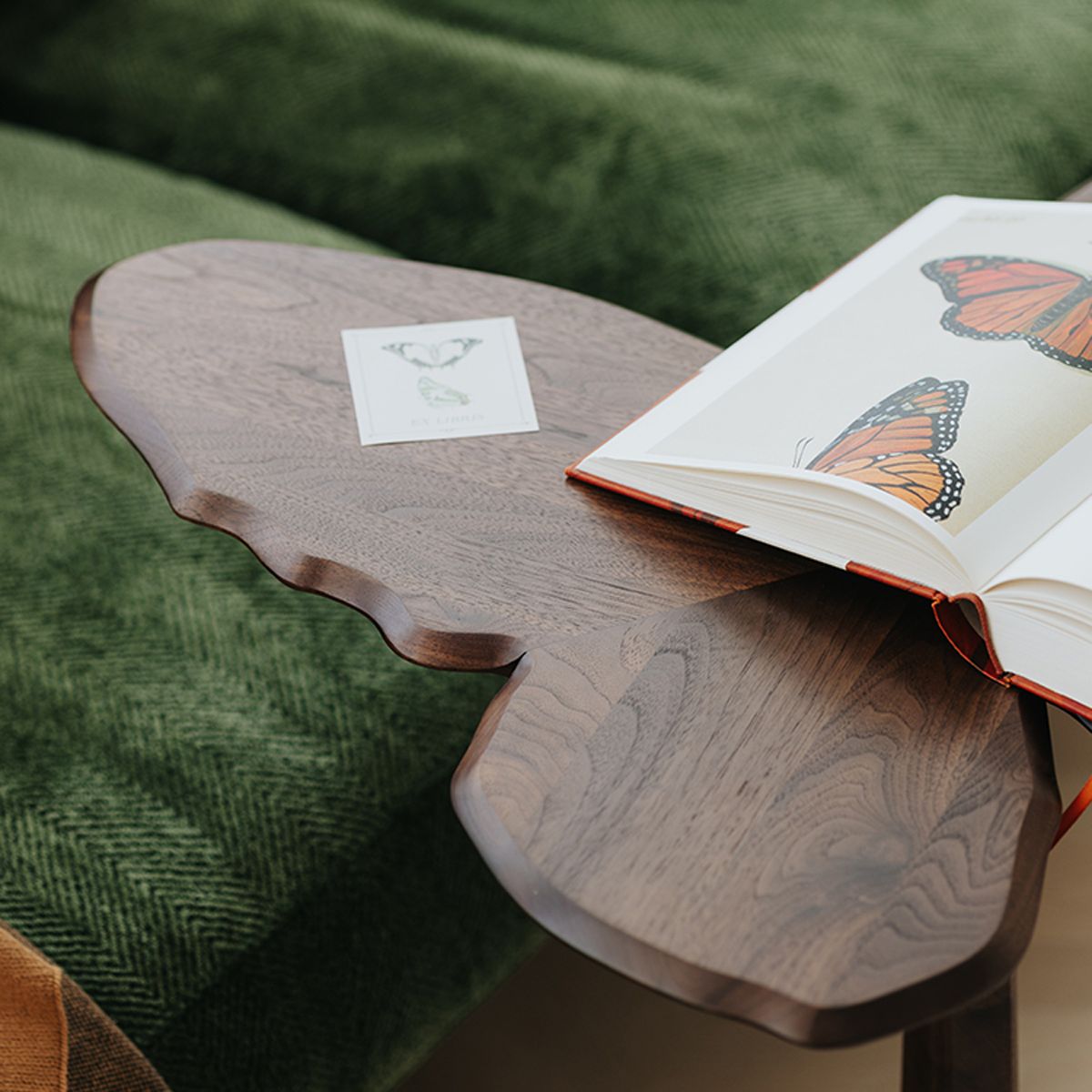 Close-up detail of the hand-carved edges on the solid walnut butterfly end table with book.