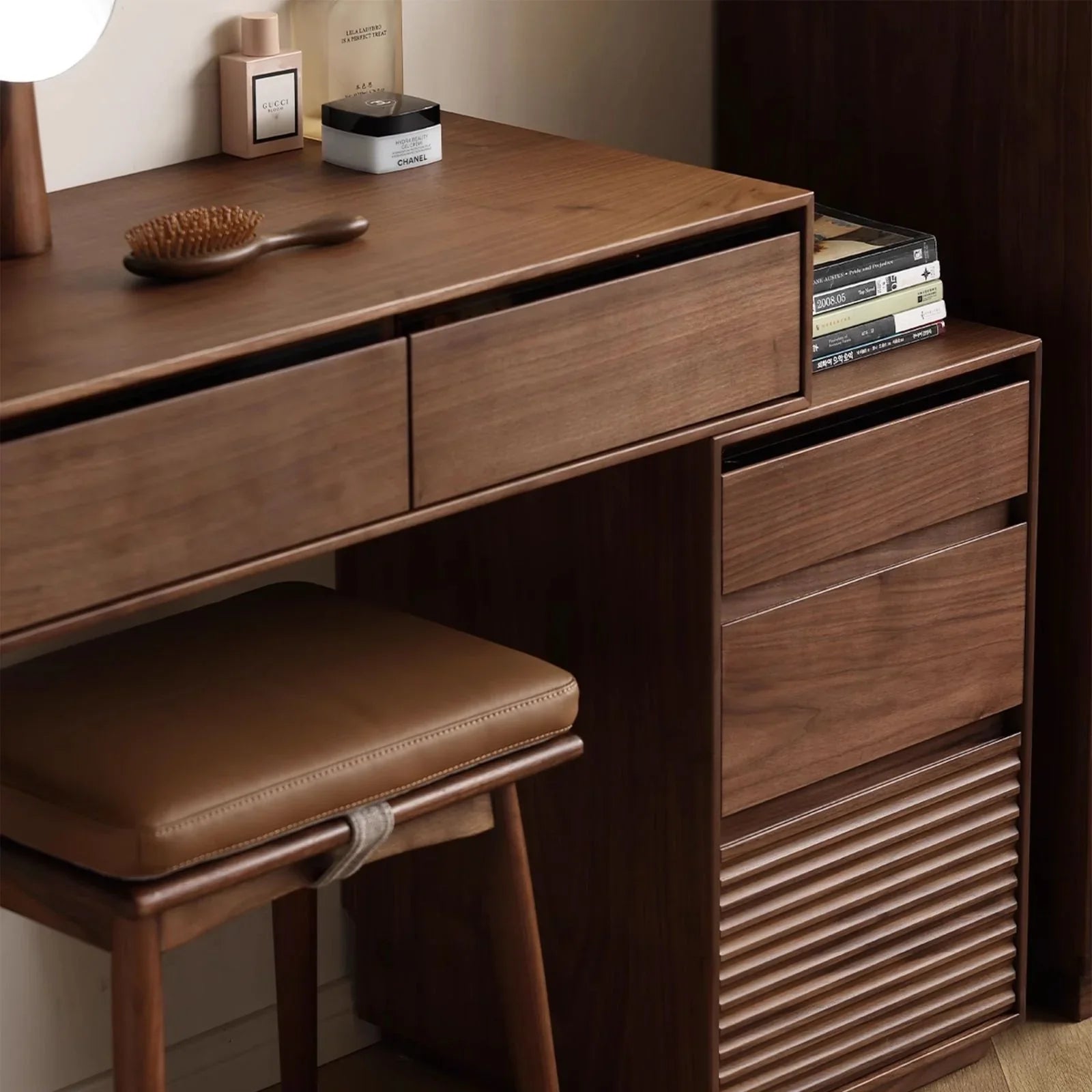 Wooden bedside table and makeup desk with drawers, leather cushioned stool, and beauty products on top