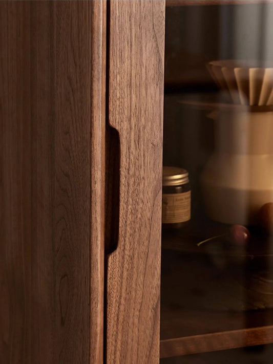 Detail of the handcrafted integrated solid wood handle on the Kurumi narrow display cabinet door.