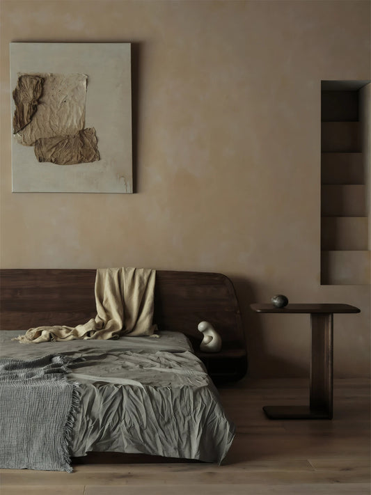 Wide shot of a serene Zen bedroom featuring the Suiseki walnut side table with a slide-under base next to a low platform bed.