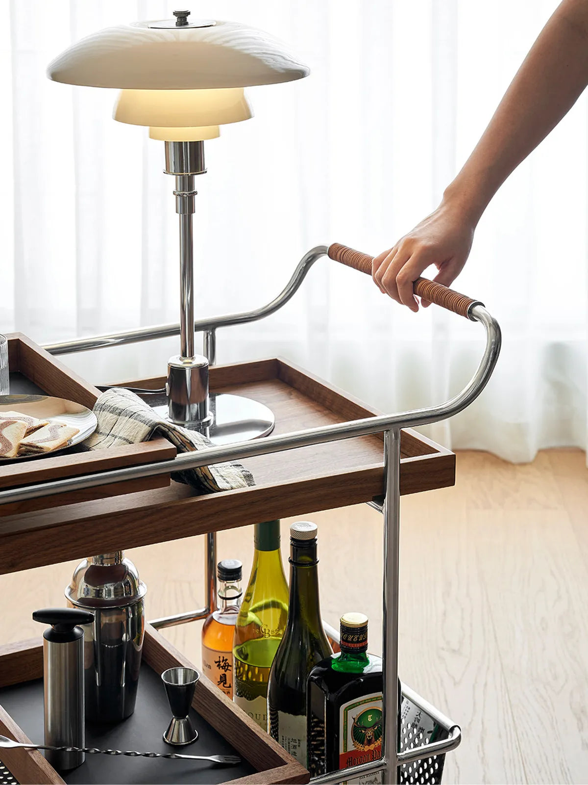 Detail shot of the hand-wrapped saddle leather handle on the chrome frame of the Walnutry serving cart.
