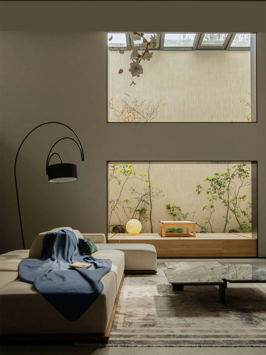 Large Kyoto low profile walnut sectional sofa in a spacious Japandi living room with skylights and courtyard view.