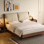 Modern bedroom with wooden bed frame, large cushioned beige headboard, striped bedding, and geometric rug