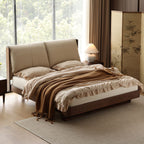 Luxury master bedroom with beige plush cloud bed, wooden frame, brown knit throw, and modern bedside lamp