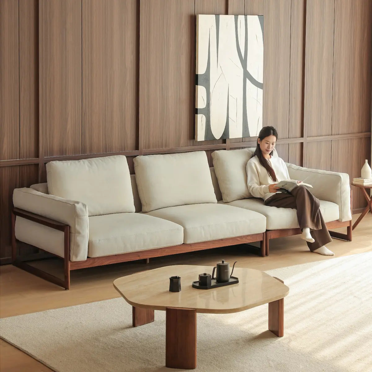 Wide angle view of a modern living room featuring a large solid wood walnut sofa and matching coffee table.