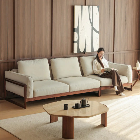 Wide angle view of a modern living room featuring a large solid wood walnut sofa and matching coffee table.