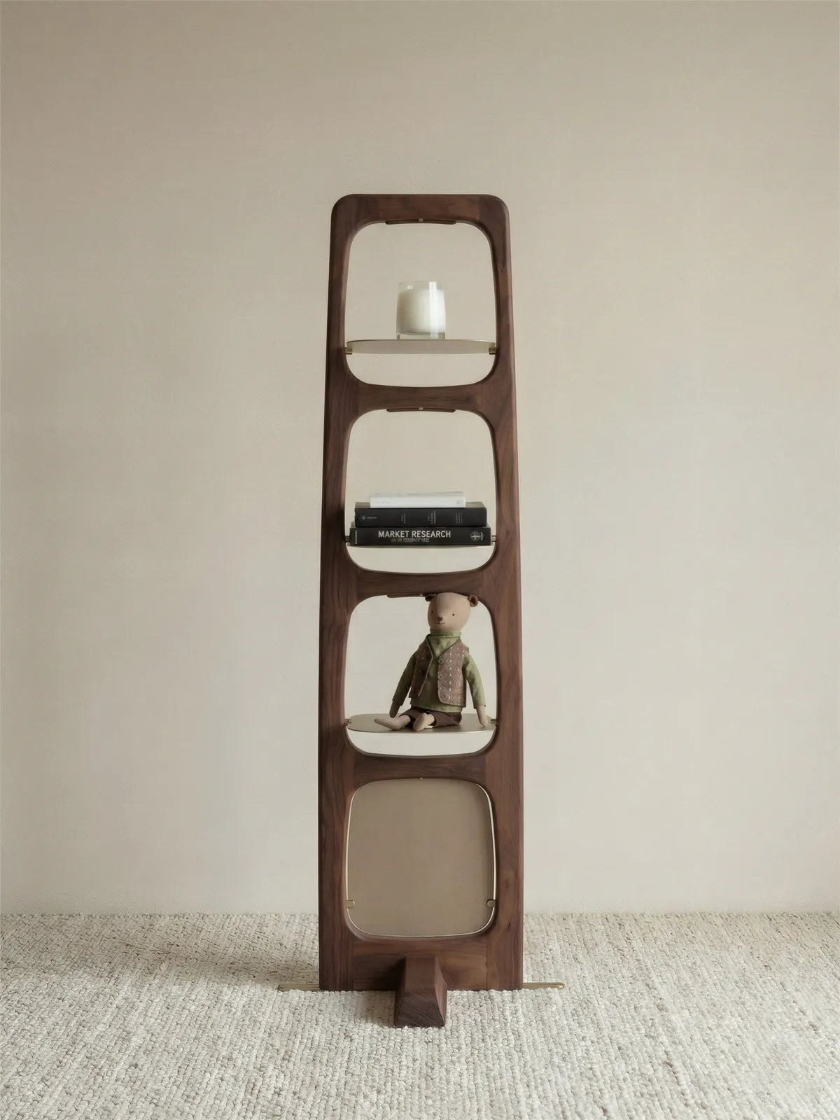 Full view of the walnut storage tower in a neutral beige room, styled with a teddy bear, books, and candles, demonstrating its versatile scale.