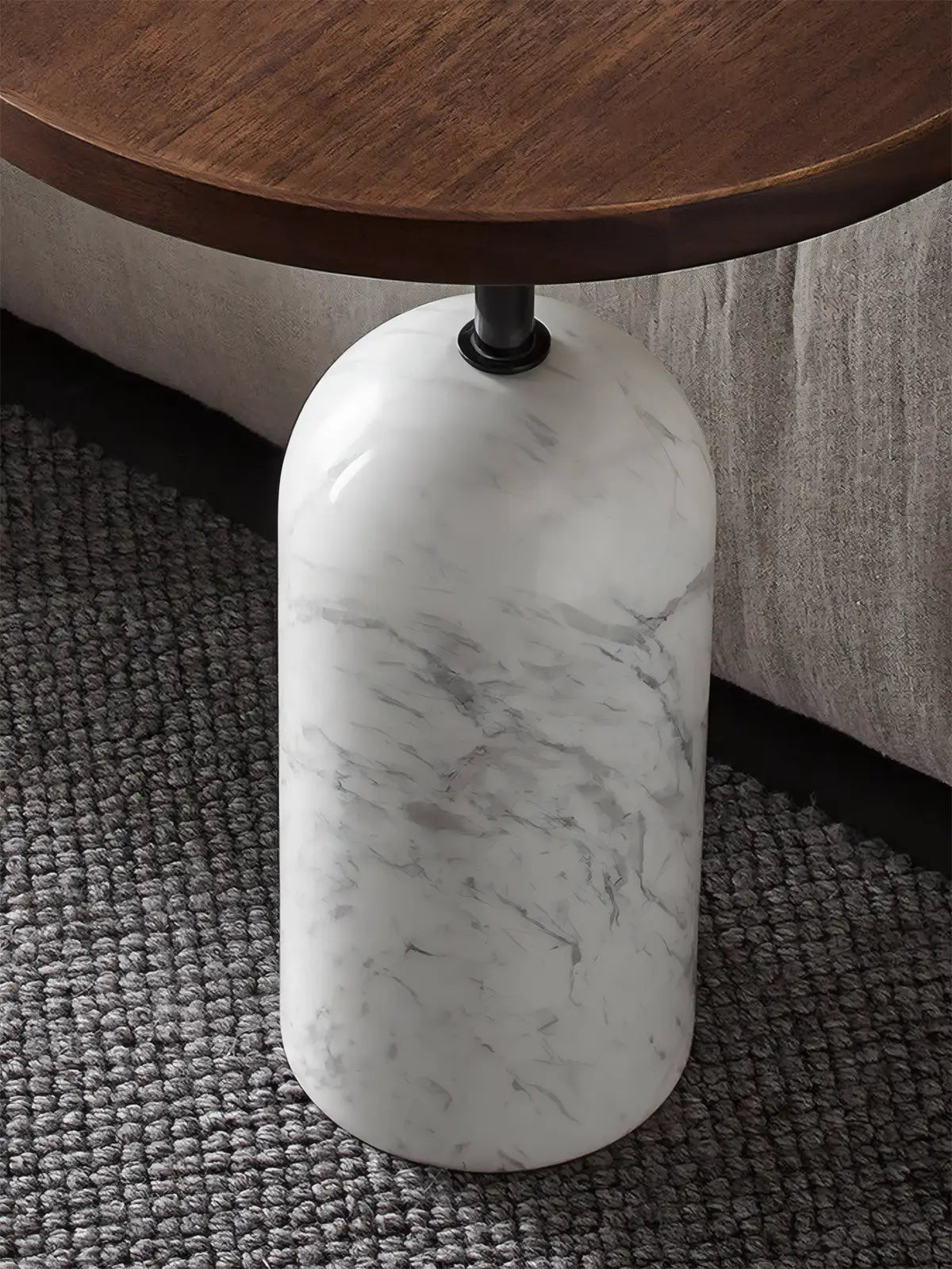 Detail shot of white marble cylindrical base connecting to a black walnut stem on a luxury drink table.