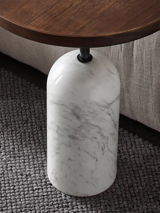 Detail shot of white marble cylindrical base connecting to a black walnut stem on a luxury drink table.