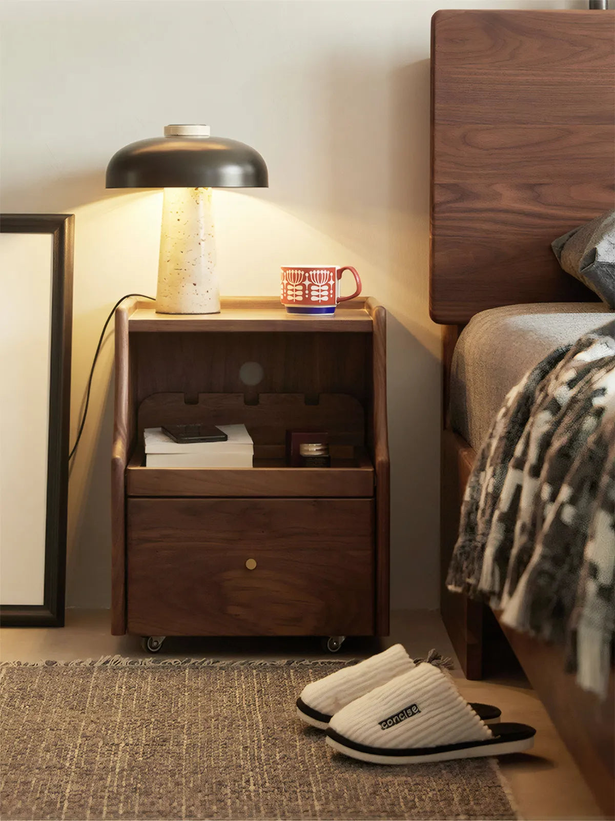 Mid-century modern walnut bedside table featuring a convenient pull-out tray for extra surface area.