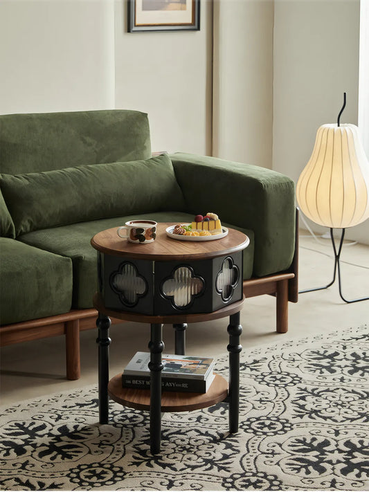 Sylvan round walnut side table placed next to a green velvet sofa in a living room.