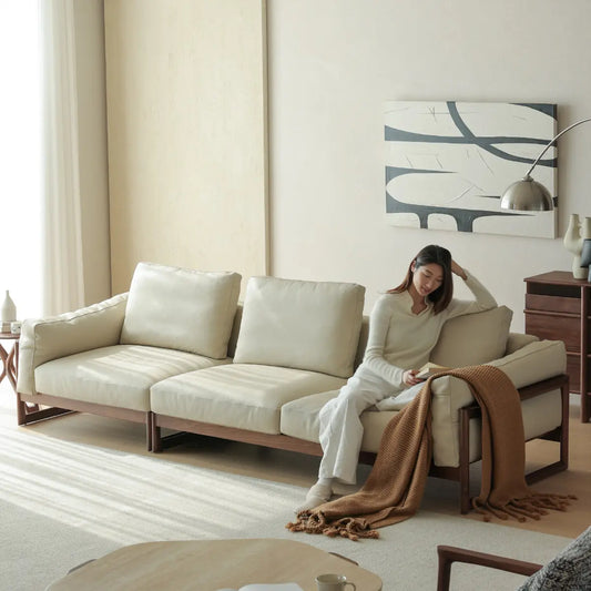 Woman reading on a comfortable deep-seat leather sofa with solid North American black walnut frame.