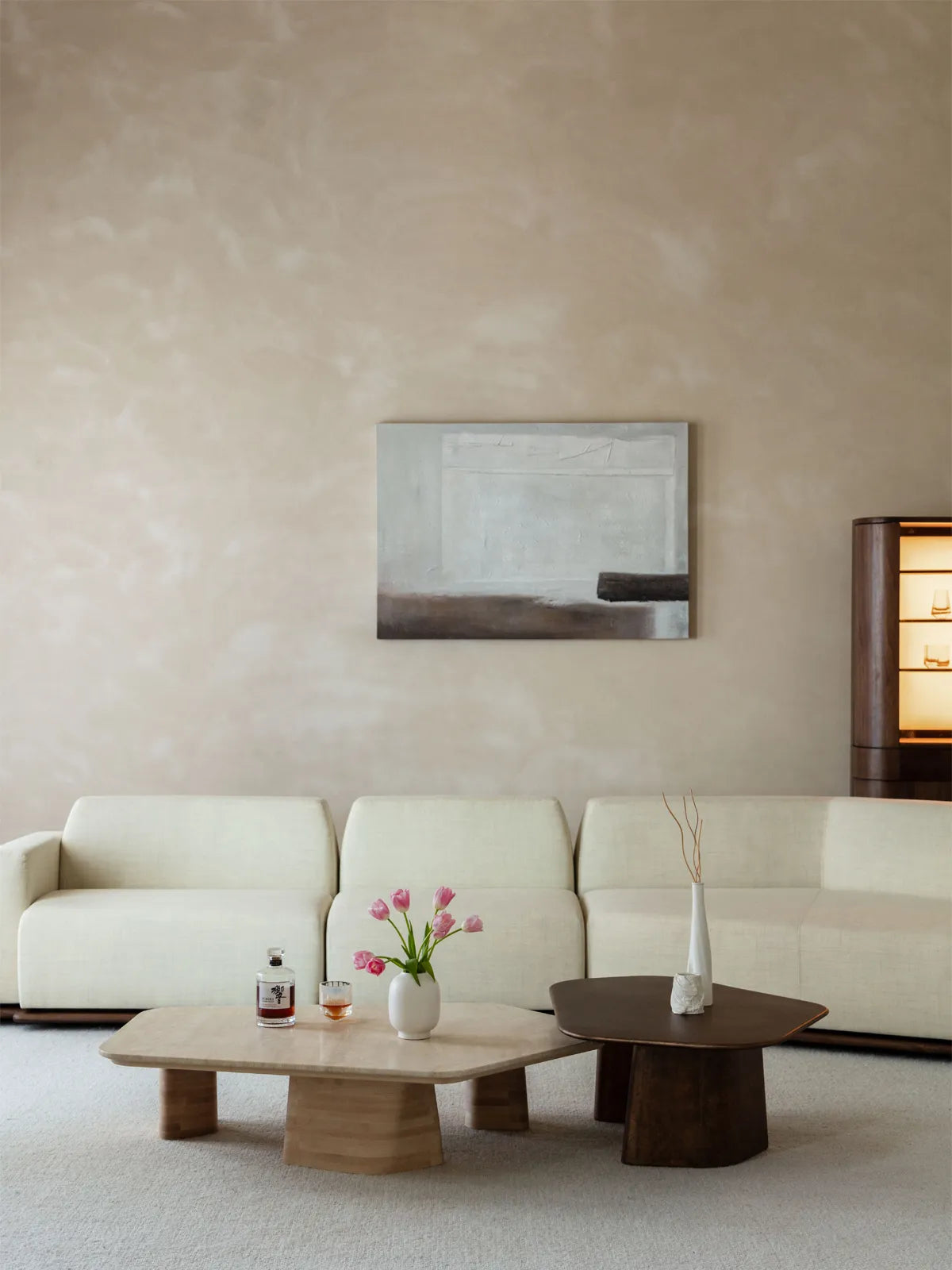 Front view of Walnutry modular sofa featuring solid walnut frame, styled with tulips and abstract art in a beige room.