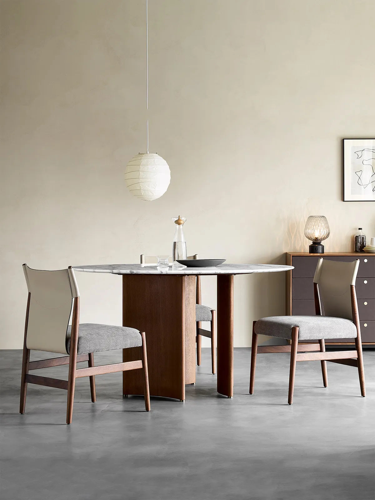 Three-quarter angle view emphasizing the mixed material design, contrasting the dark walnut wood frame with light cream upholstery.