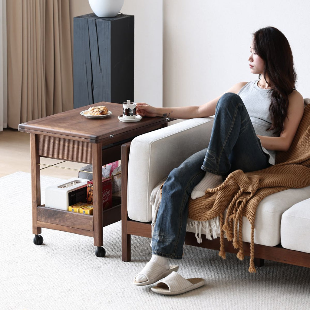Woman relaxing on beige sofa with brown knit blanket and wooden side table holding coffee and pastry