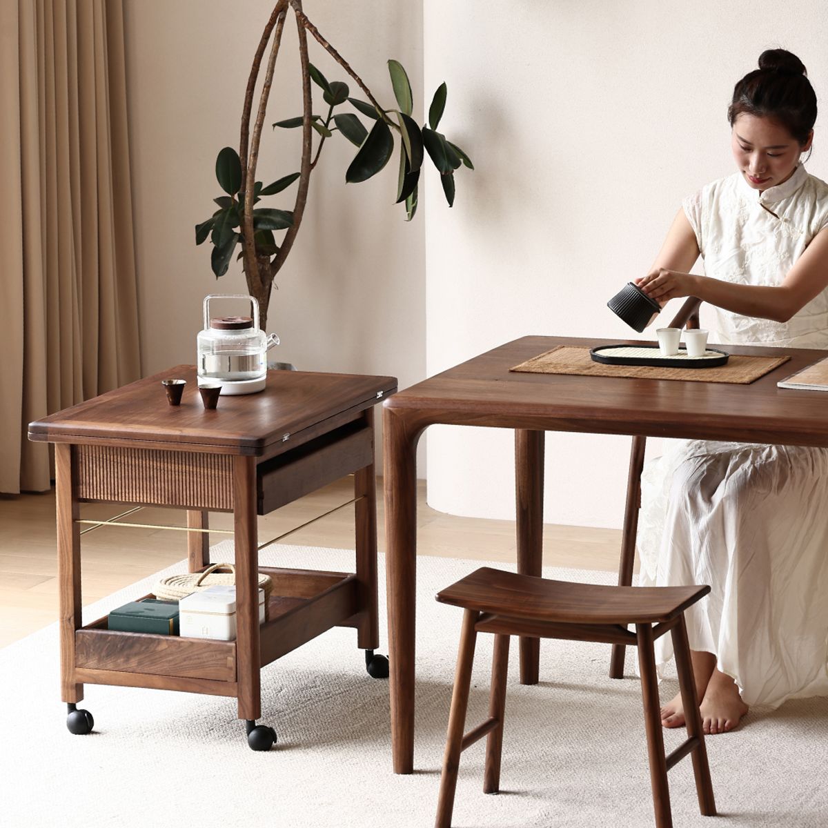 Modern wooden tea cart and table with woman in white dress pouring tea in minimalist room