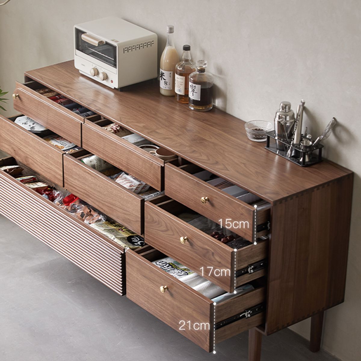 Modern walnut dresser with open drawers showing organized storage and kitchen accessories on top