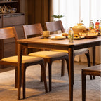 wooden dining table with upholstered chairs set with plates, cups, bottles, and food in modern dining room