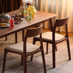 Modern dining room setting featuring a set of comfortable white leather and walnut chairs.