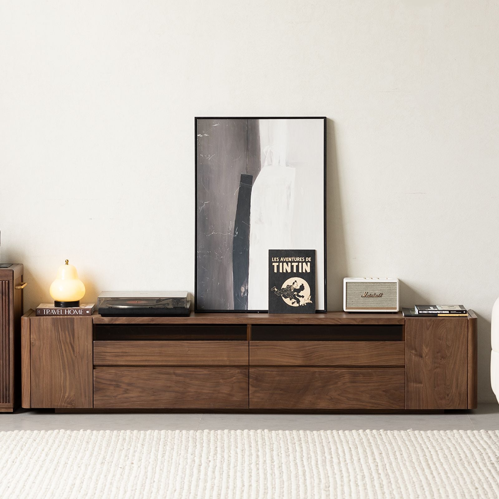 Modern walnut entertainment center with abstract art, record player, lamp, books, and Marshall speaker