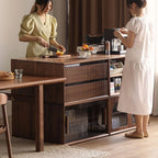 Two women using a modular walnut kitchen storage system with drawers and glass cabinets