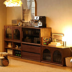 Modular walnut storage system with glass doors in cozy room with espresso machine and decorative items