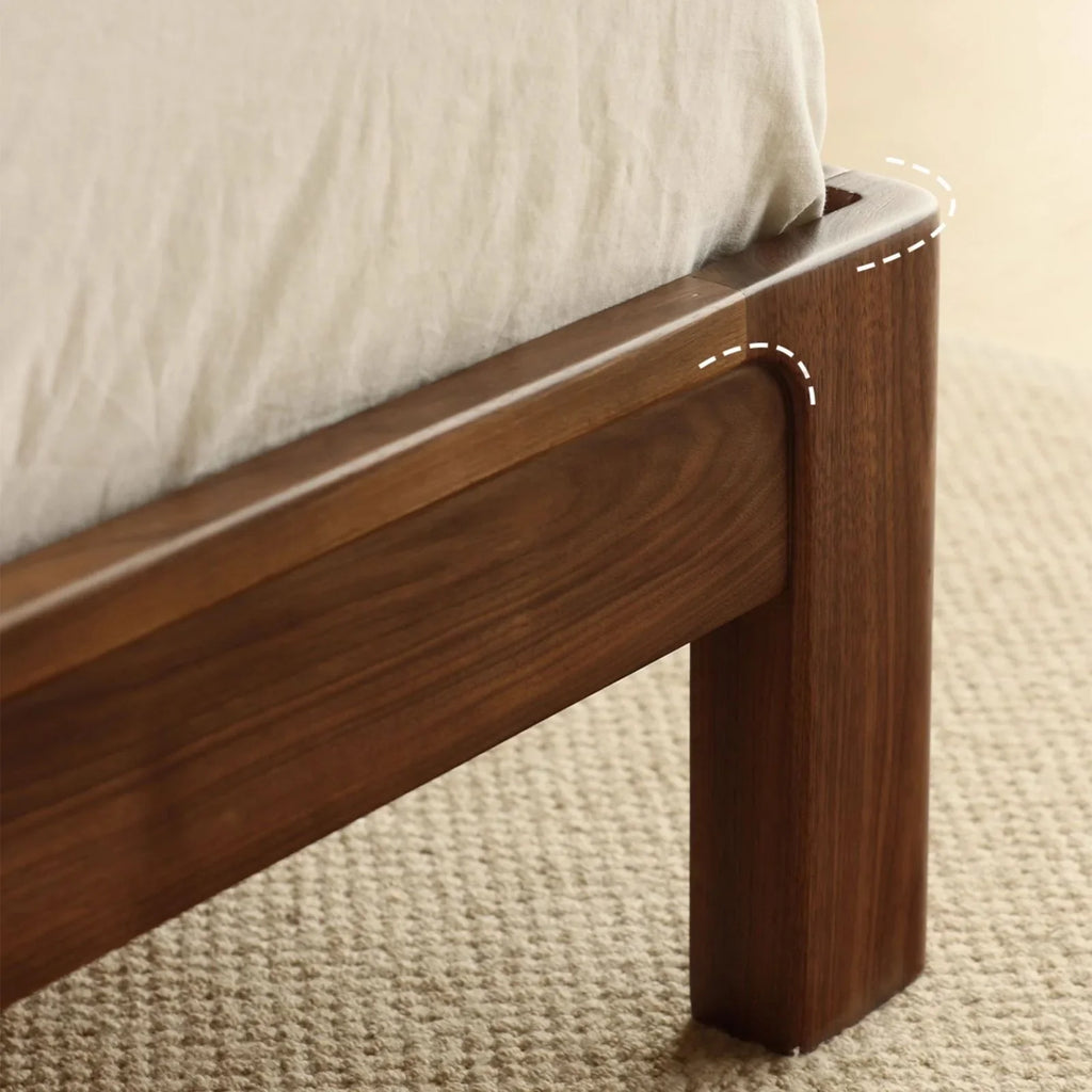 Close-up of natural walnut wood grain bed frame leg on beige textured carpet
