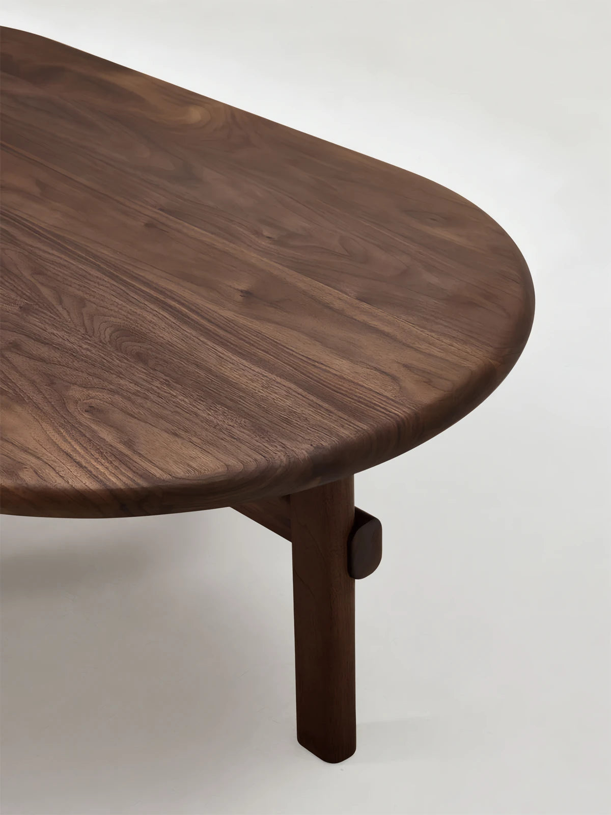 Alt Text: The Suiseki Pebble Table by Walnutry in solid black walnut, featuring an organic oval shape in a minimalist Japandi living room.