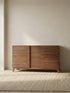 The Opus 60-inch solid wood console table in a minimalist setting with natural light, showcasing the linear design and warm walnut tones.