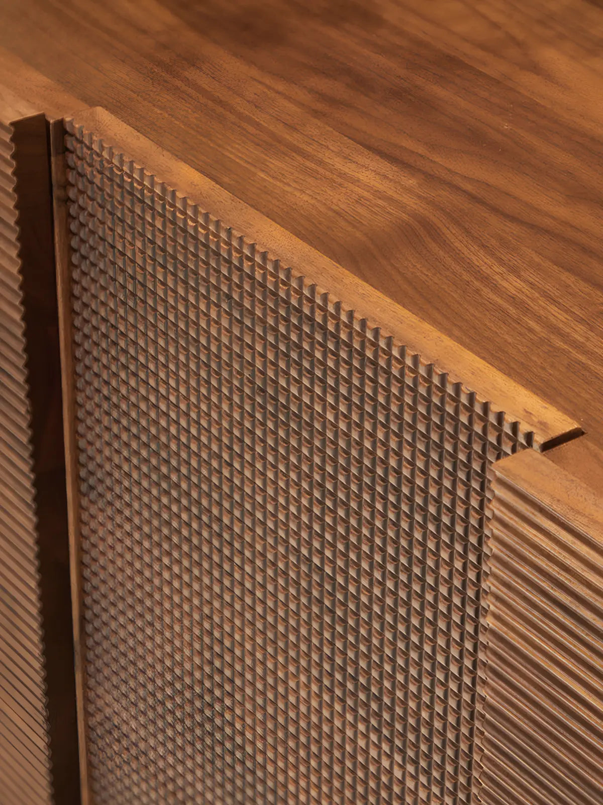 Close-up detail of The Opus console showing the handcrafted joinery and contrasting texture between the linear slats and the central grid pattern on solid walnut.
