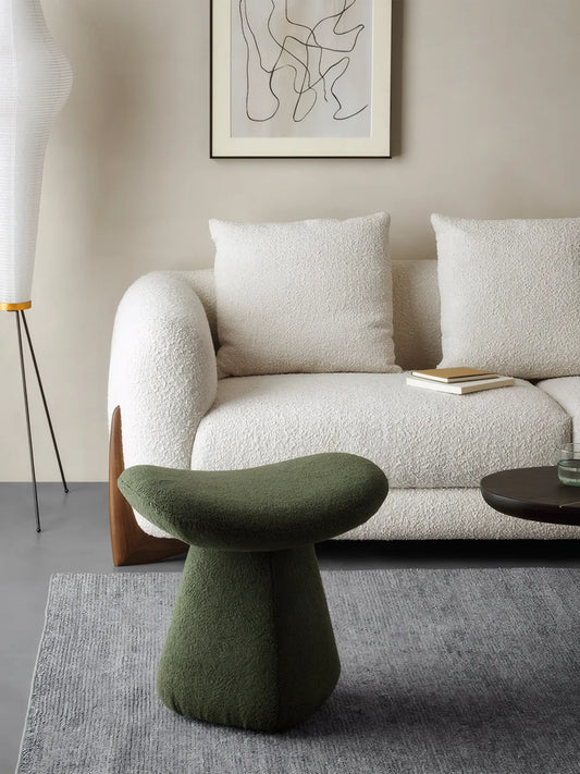 A sculptural green mushroom stool styled in a modern minimalist living room with a white boucle sofa, demonstrating Japandi interior design trends.

