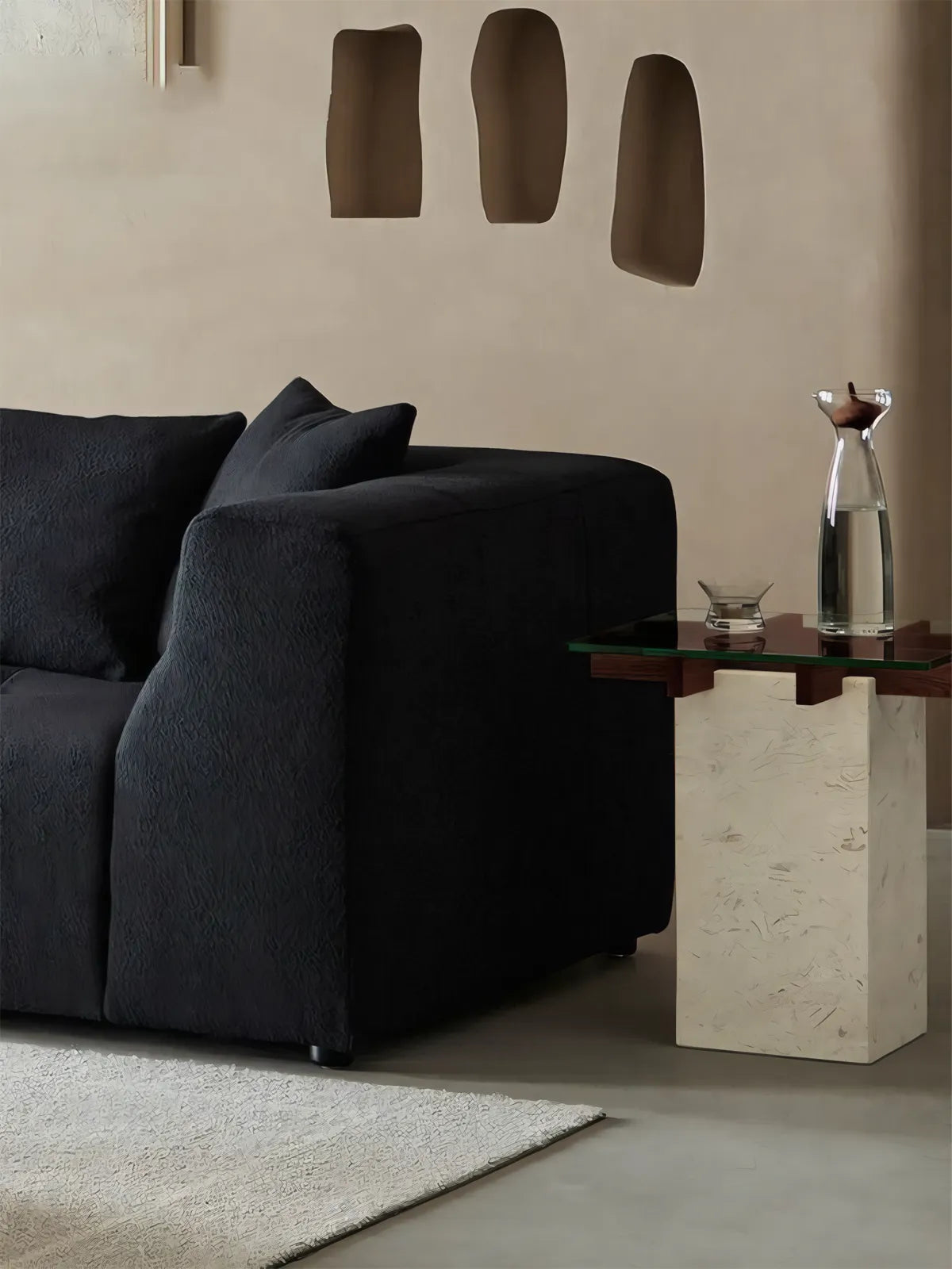 Dark sofa styled with Cumberland mixed material side table featuring glass top and stone base.