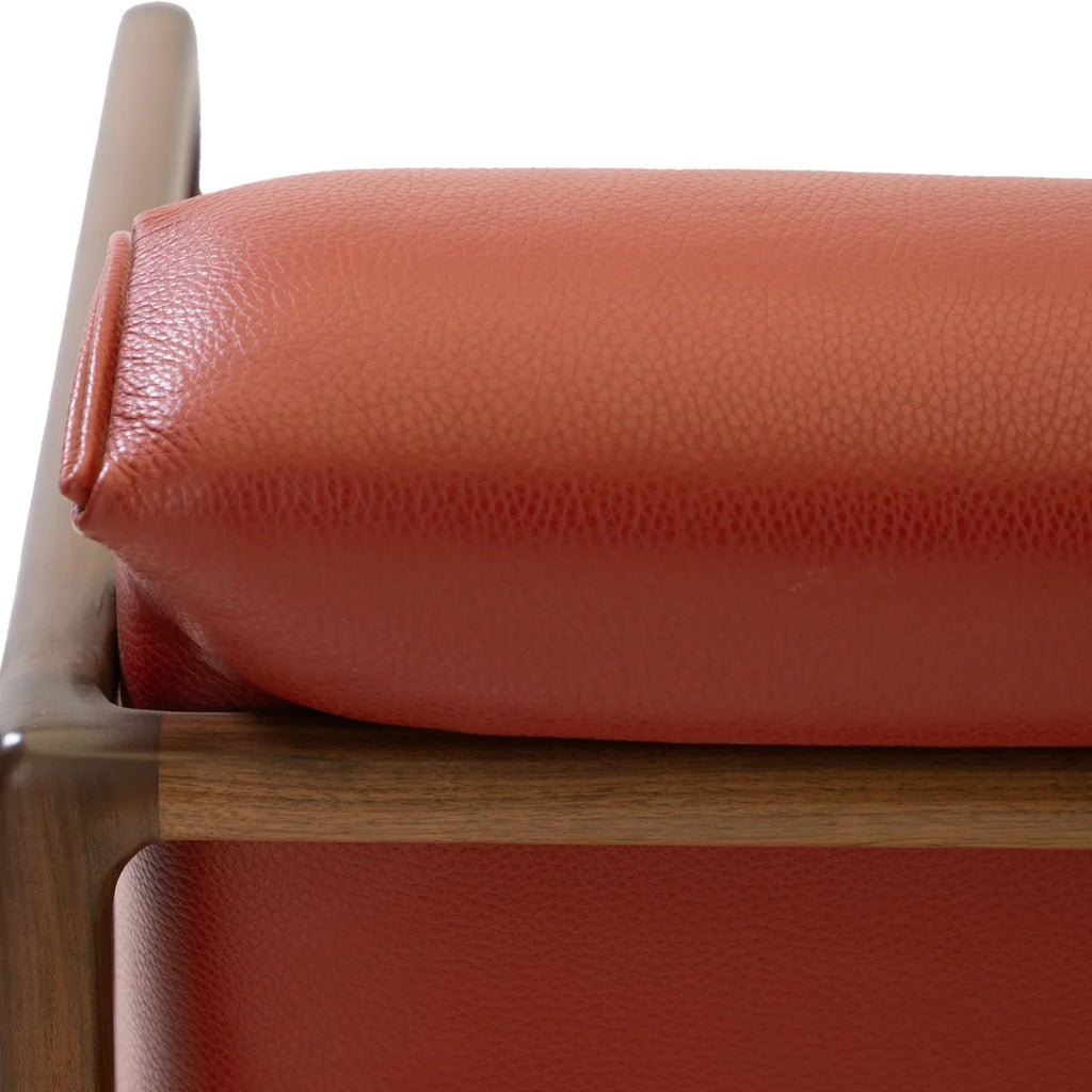 Close-up of the premium top-grain oxblood leather upholstery on the walnut lounge chair.