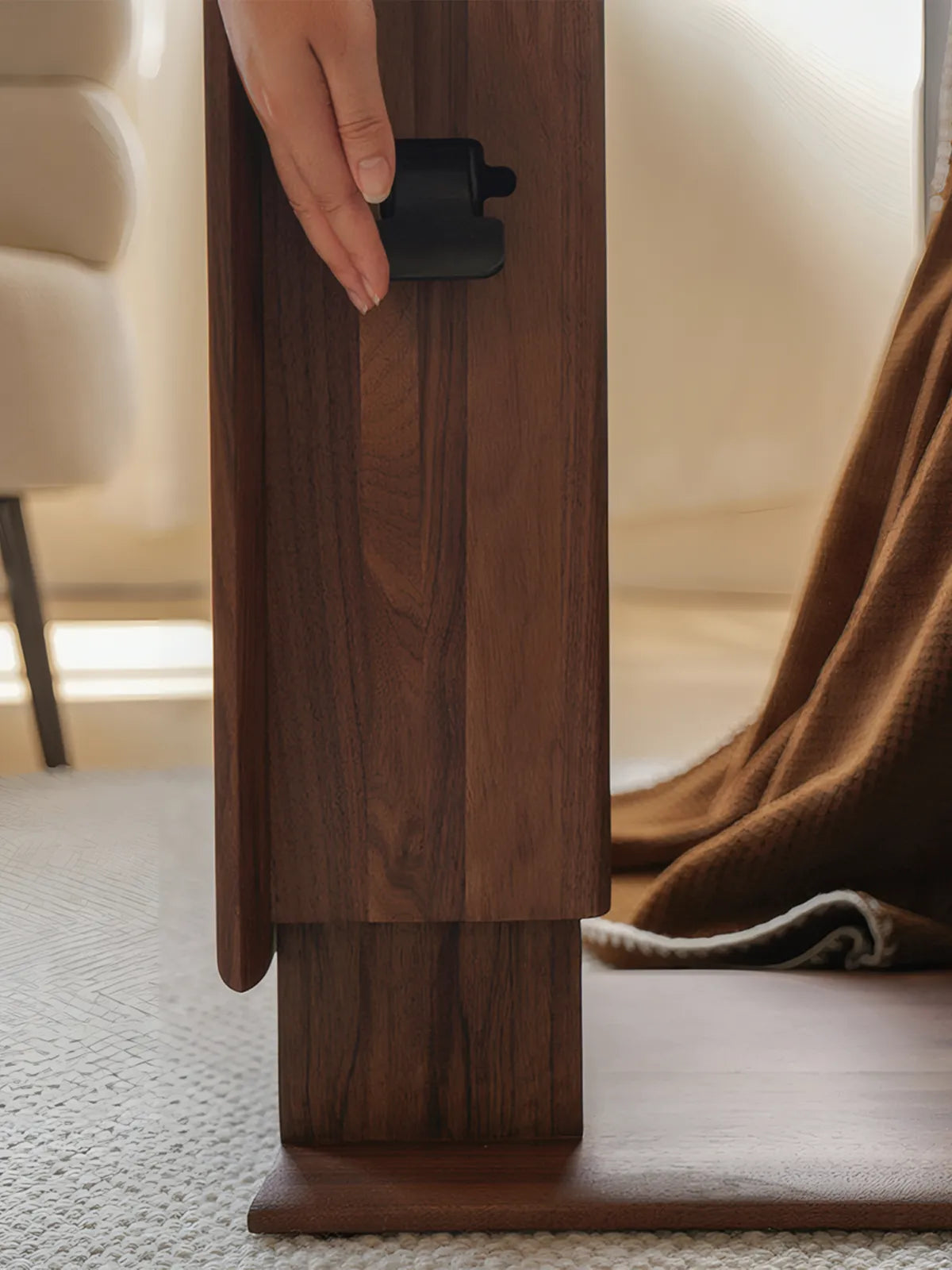 Hand operating the silent pneumatic lift paddle on the walnut side table.