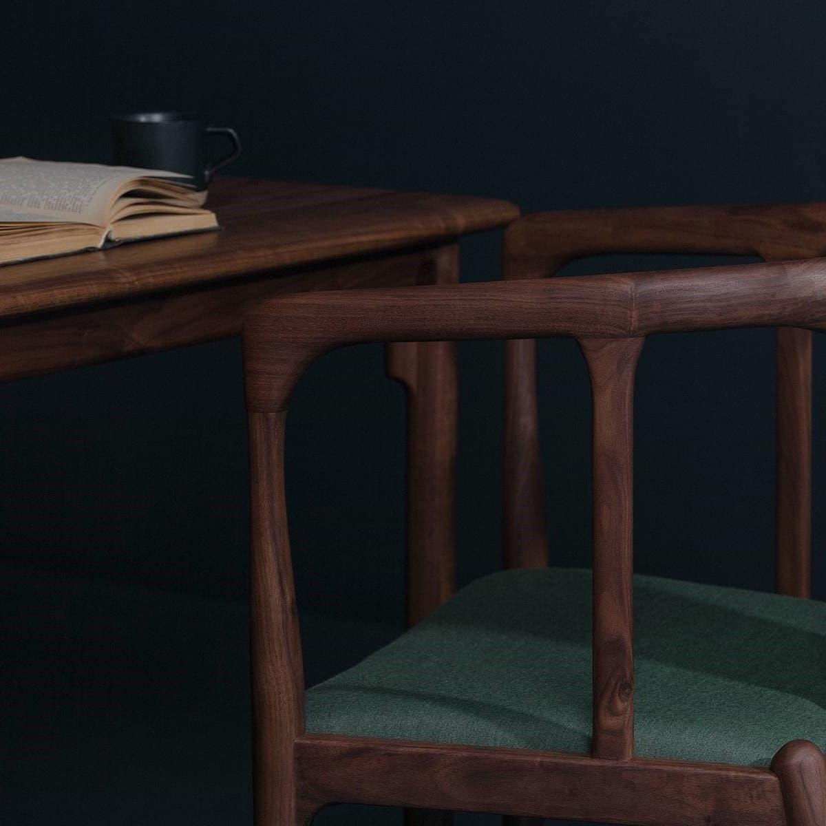 Close-up detail of a dark walnut armchair with a green upholstered seat, highlighting the smooth curved armrest design and joinery in a moody reading corner.