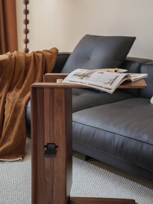 The Curator walnut table raised to 25 inches for laptop use on a grey sofa.