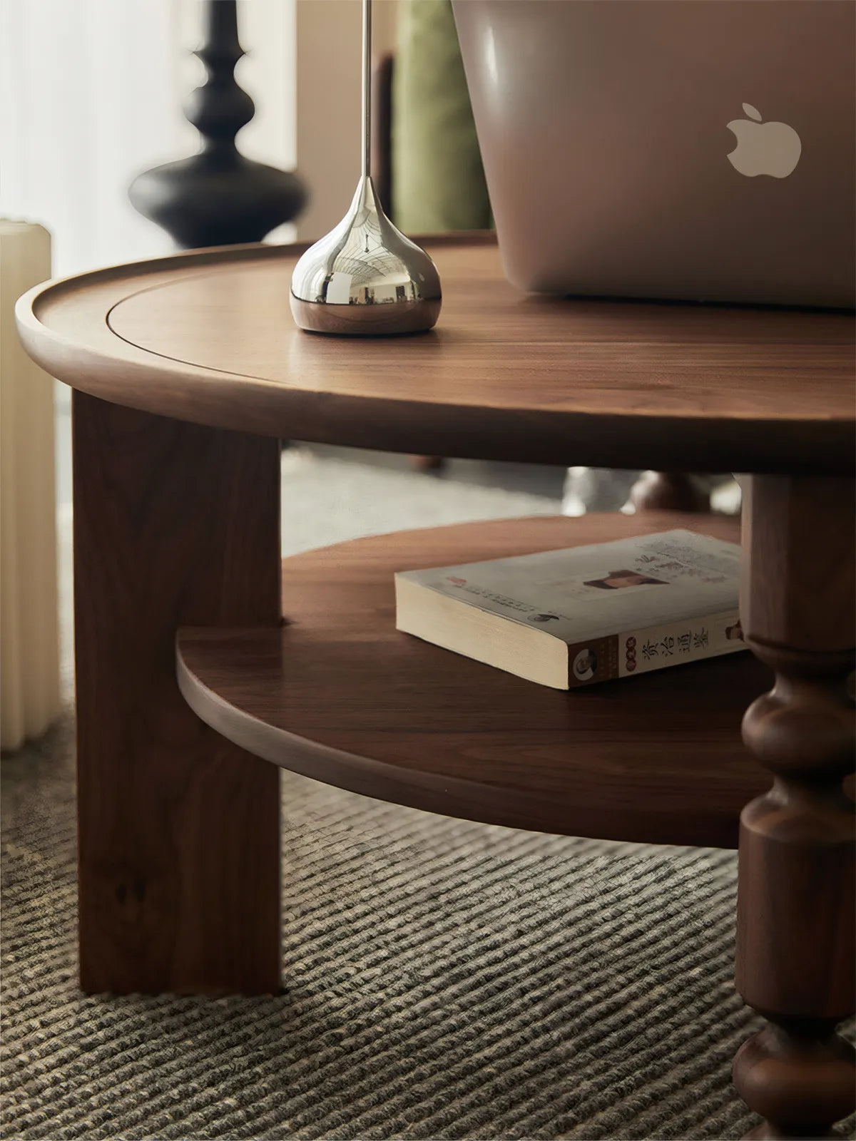 Side profile of Sylvan round coffee table featuring a lower storage shelf and mid-century modern turned tapered legs.