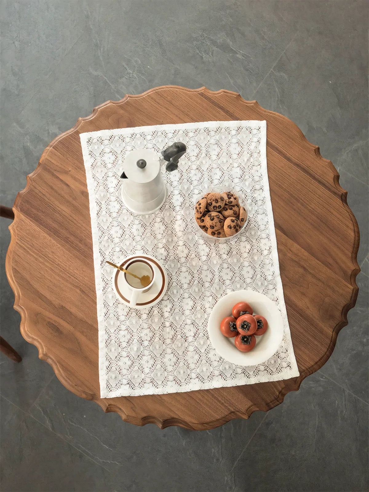 Top-down view of the Margaux table showing the intricate scalloped edge detail and rich black walnut grain with coffee and cookies.