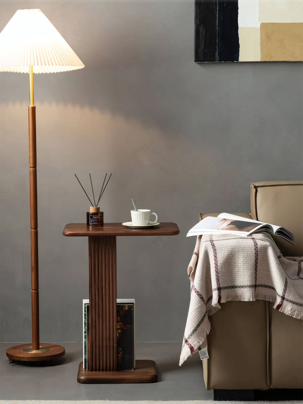Meridian C-Table positioned next to a modern grey sofa in a small apartment, styled with a coffee cup and book, demonstrating space-saving functionality.