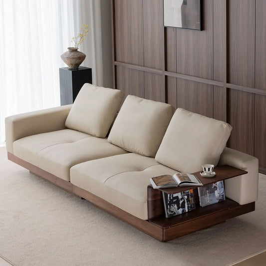 Integrated side table and storage shelf built into the walnut sofa armrest, displaying books and decor.